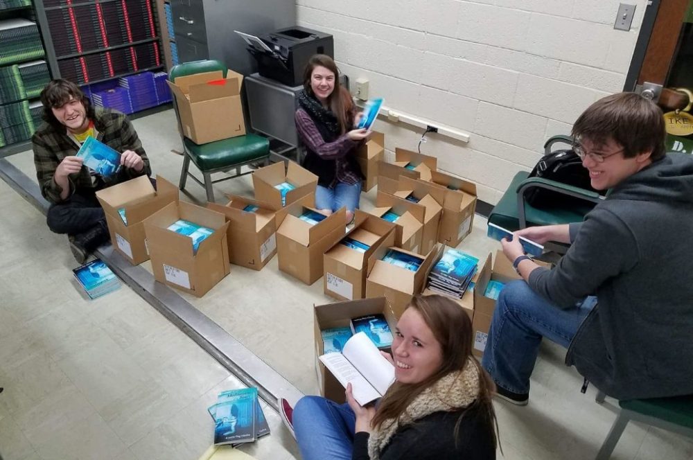 Cornerstone Press student staff members unbox one of the books they published. The press is marking 40 years with a gala event in April.