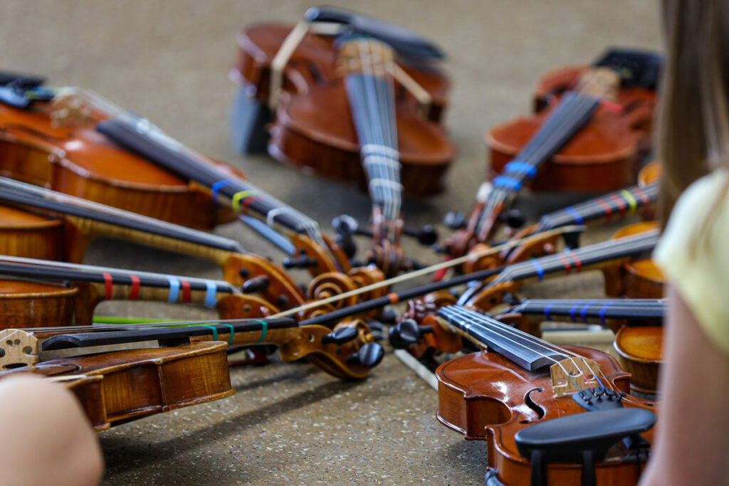 Violins arranged in a circle on a cement floor.