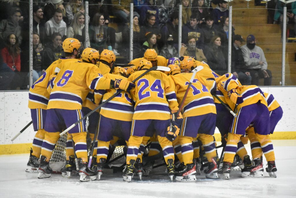 Men's hockey team huddle on the ice during a game.