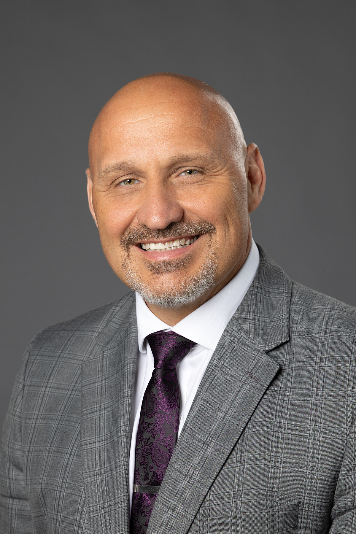 Headshot of man in a suit smiling at the camera.
