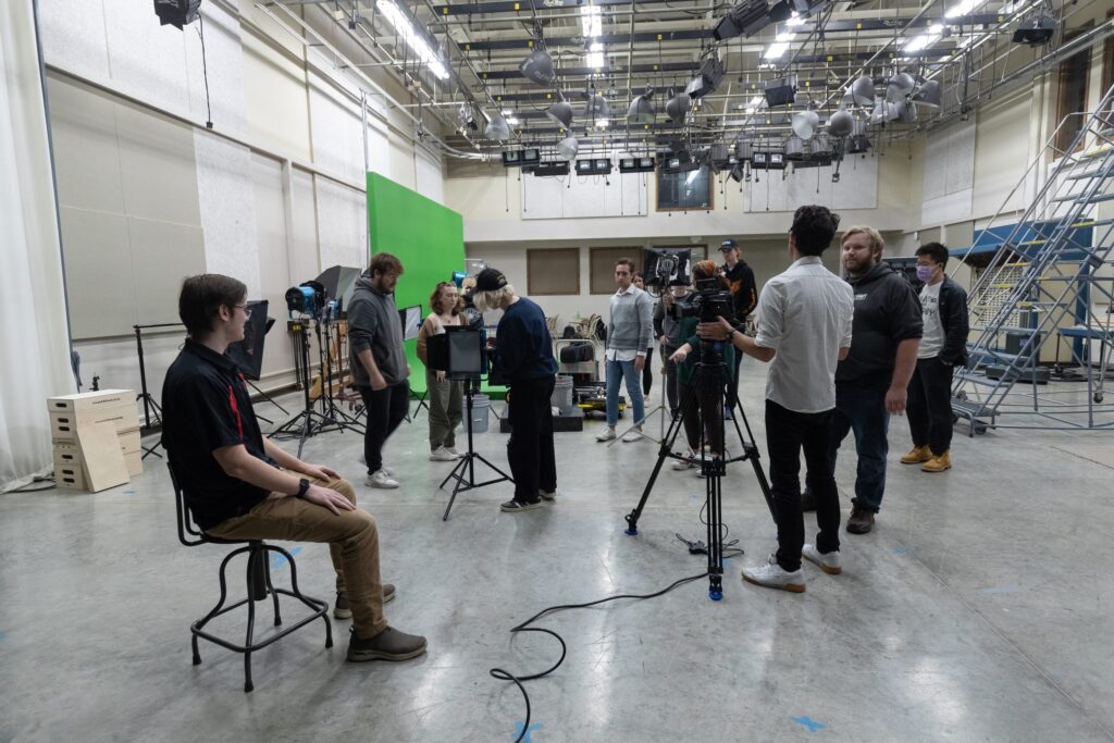 People working in a video studio with lighting and green screen.