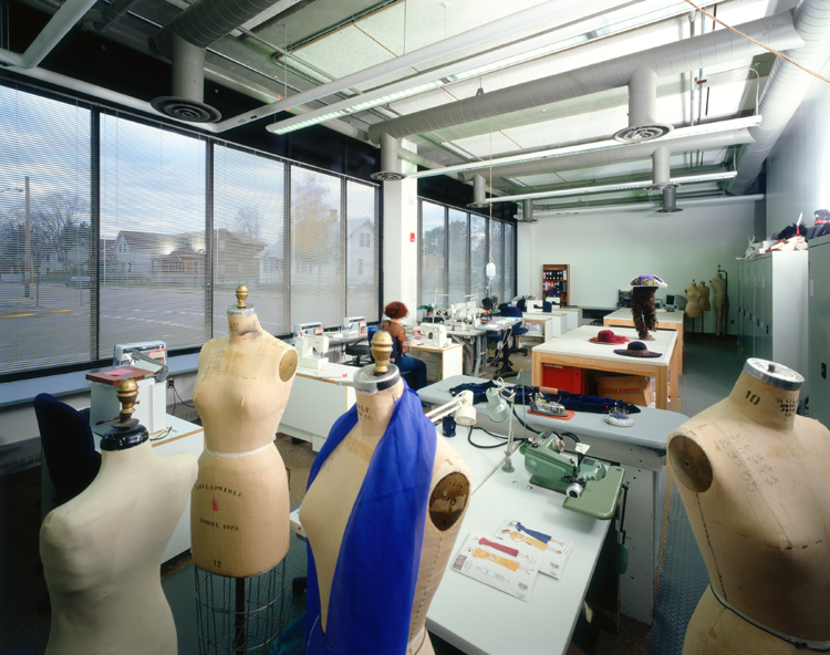 Room with sewing machines and dress forms.