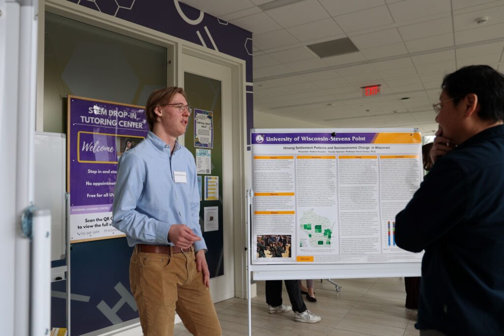 Student shares research poster with sociology professor David Chunyu at Undergraduate Research Symposium