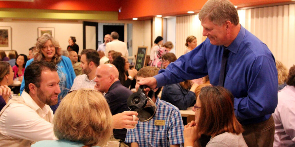 Faculty member pouring coffee for colleagues in a cafe.
