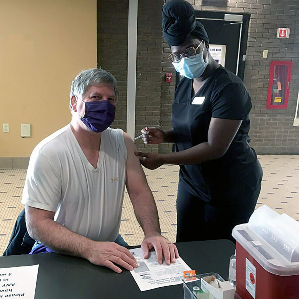 Health care worker administering a vaccination at a temporary clinic table.