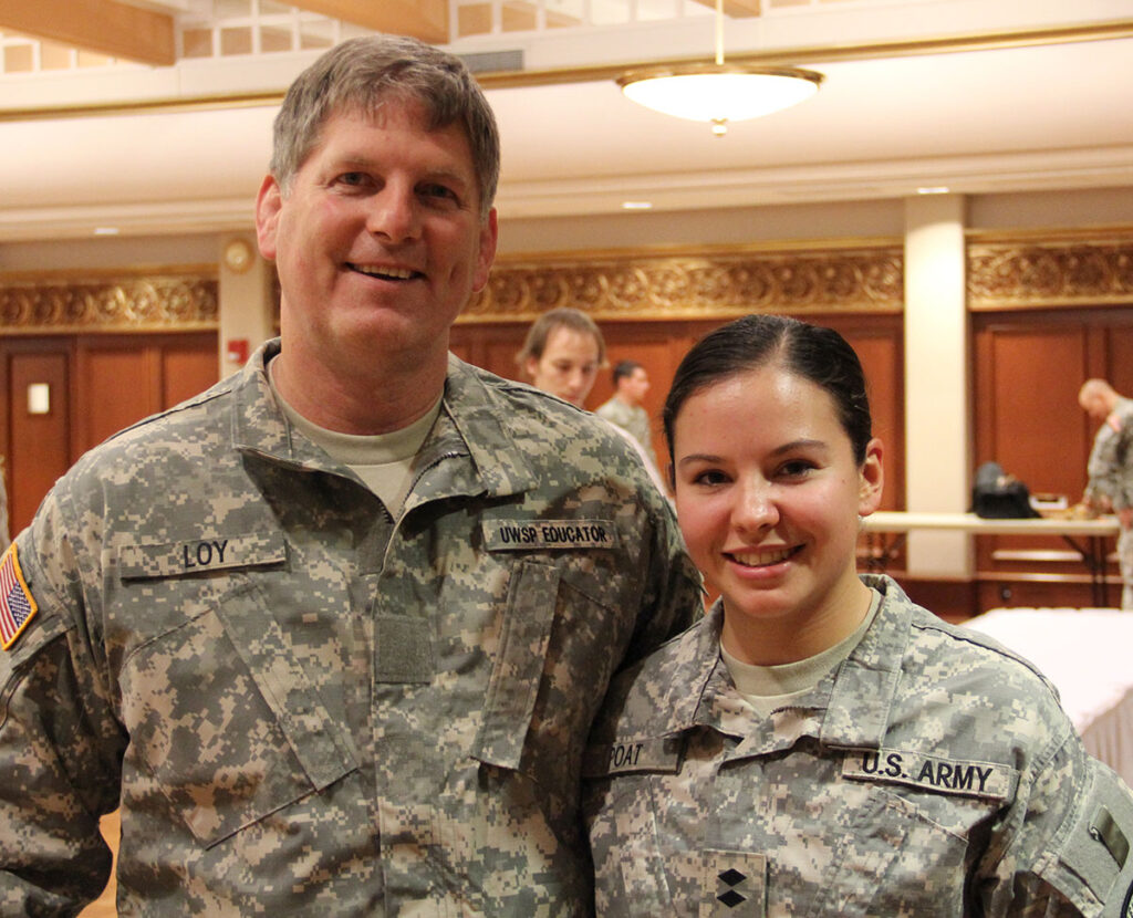 Two adults in military attired indoors during a ceremony.