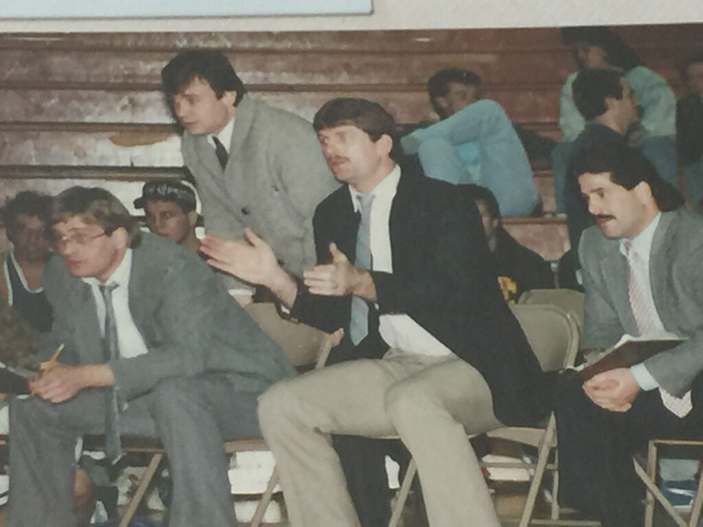 Attendees seated in folding chairs inside a gymnasium during a wrestling match.
