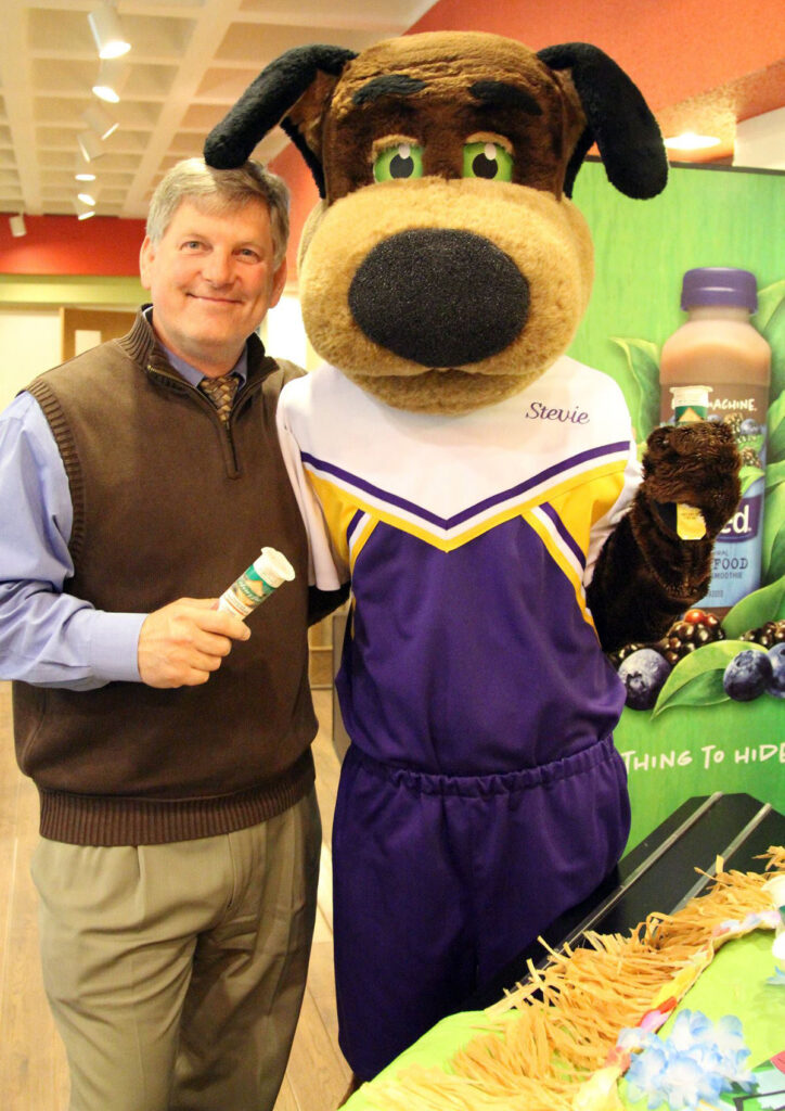Adult standing next to the Stevie Pointer mascot at a campus event.
