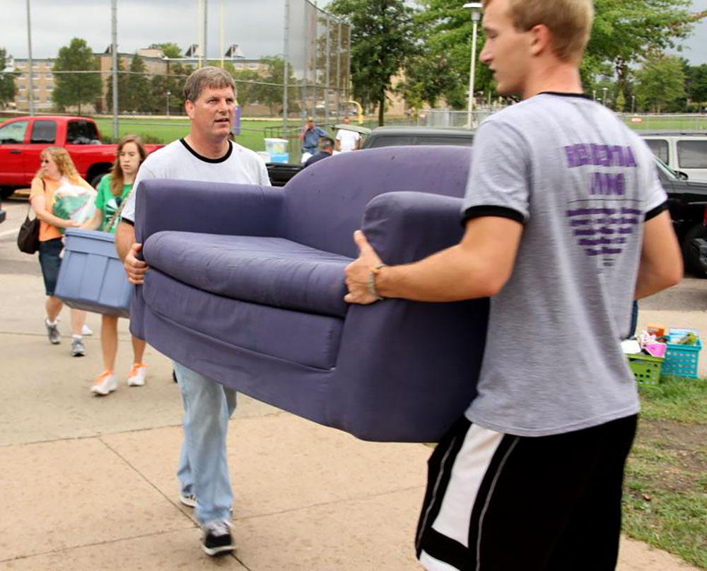 Two adults carrying a couch together during a move-in event.