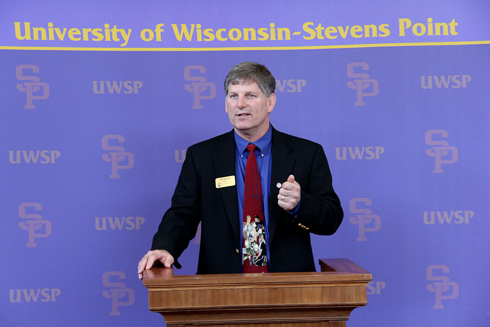 Faculty at a university event with a UW-Stevens Point backdrop.