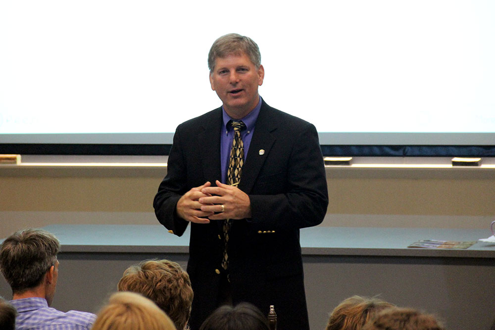 Faculty member speaking at the front of a classroom.
