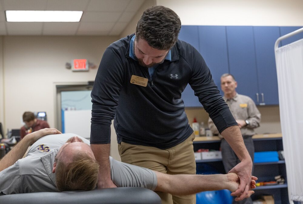 Caden Prahl, a second-year DPT student, works with a patient at the clinic under the guidance of Clinical Associate Professor Chris Durall.