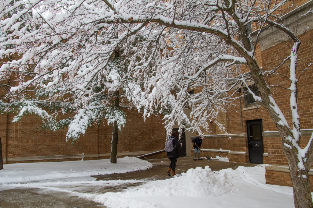 Snow and someone shoveling behind the Communication Arts Building
