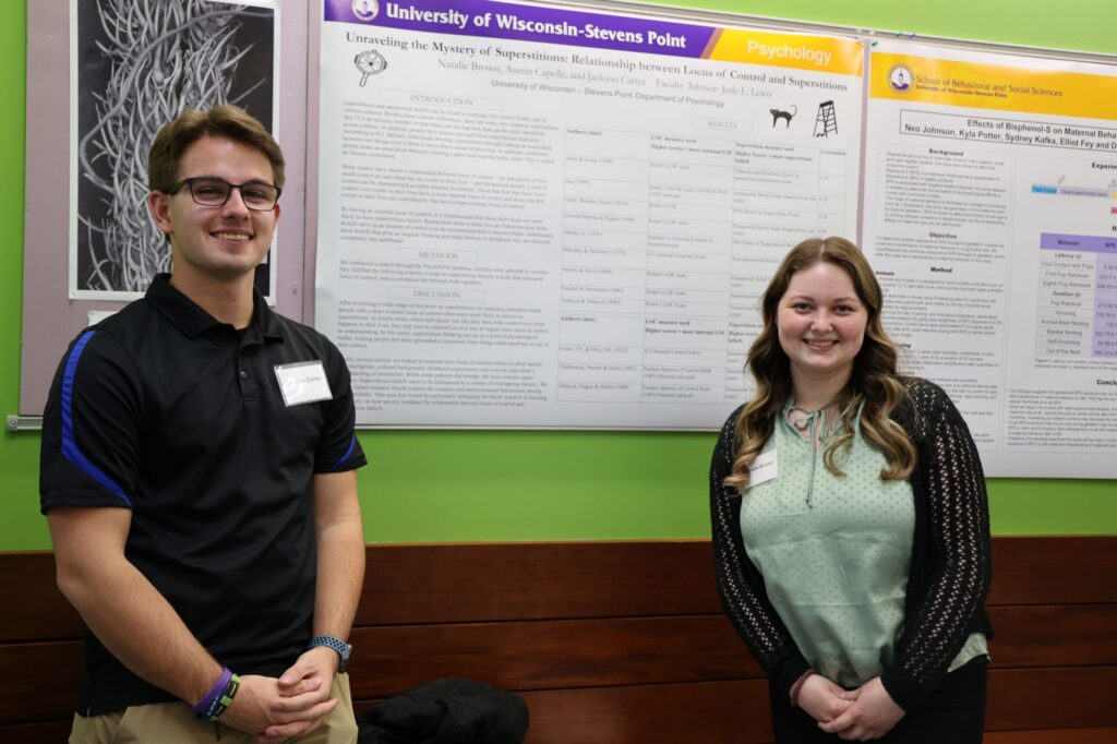 students present in front of psychology research poster