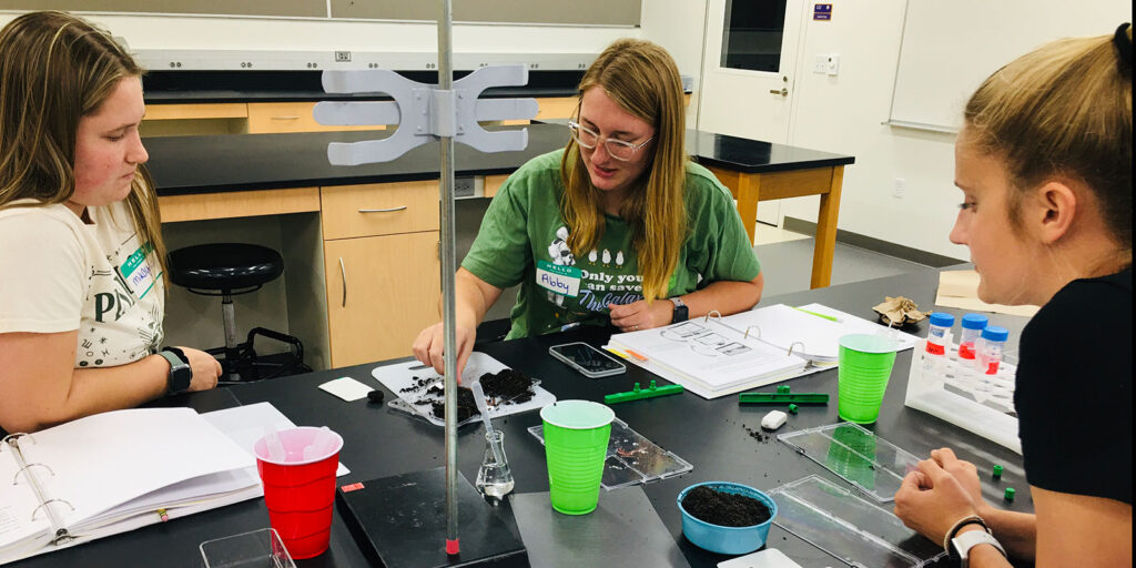 Students working in a science lab sorting materials and recording observations during a group activity.