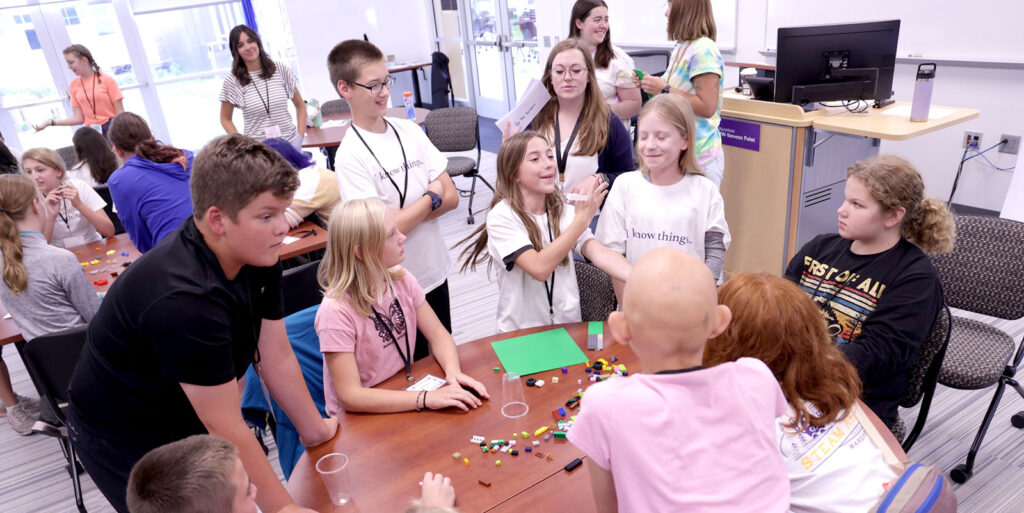 Students work together at tables on a building challenge using LEGO pieces during a classroom activity.