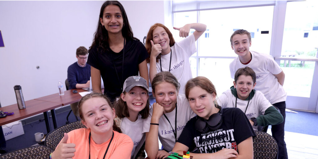 A group of students gather for a photo in a classroom during a hands-on learning activity.