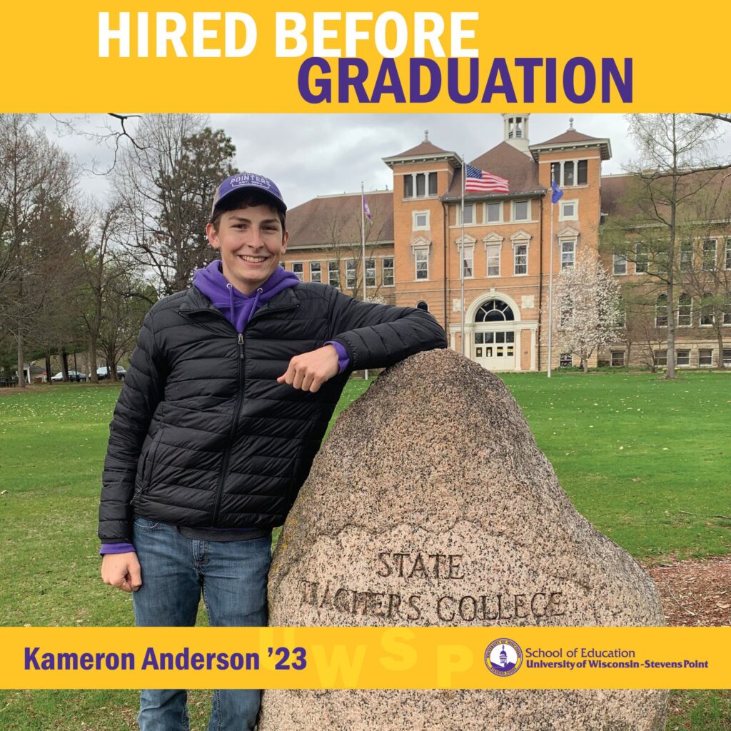 Student outdoors on campus leaning against the State Teachers College monument stone with Old Main visible behind them and “Hired Before Graduation” at the top.