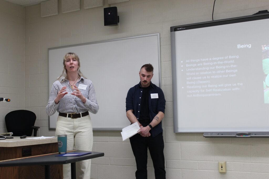 Undergraduate Research Symposium student oral presentation in a classroom. Student standing in front of a room.