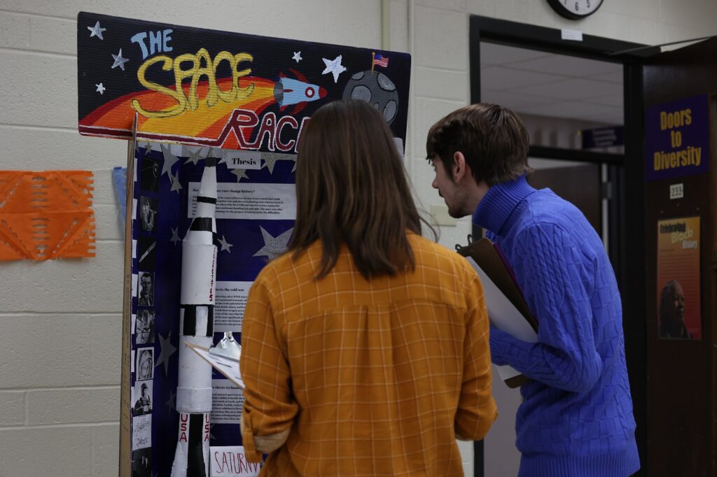 male and female judges stand in front of display on the space race.