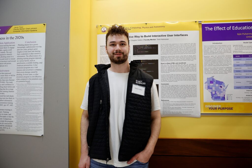 Computing major stands in front of spring research poster.