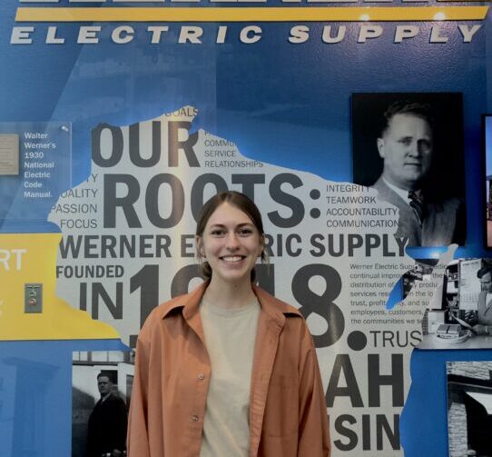 student intern stands near Werner Electric company sign