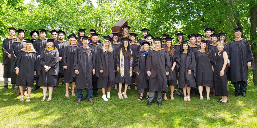 Large group of graduates posing outdoors in caps and gowns