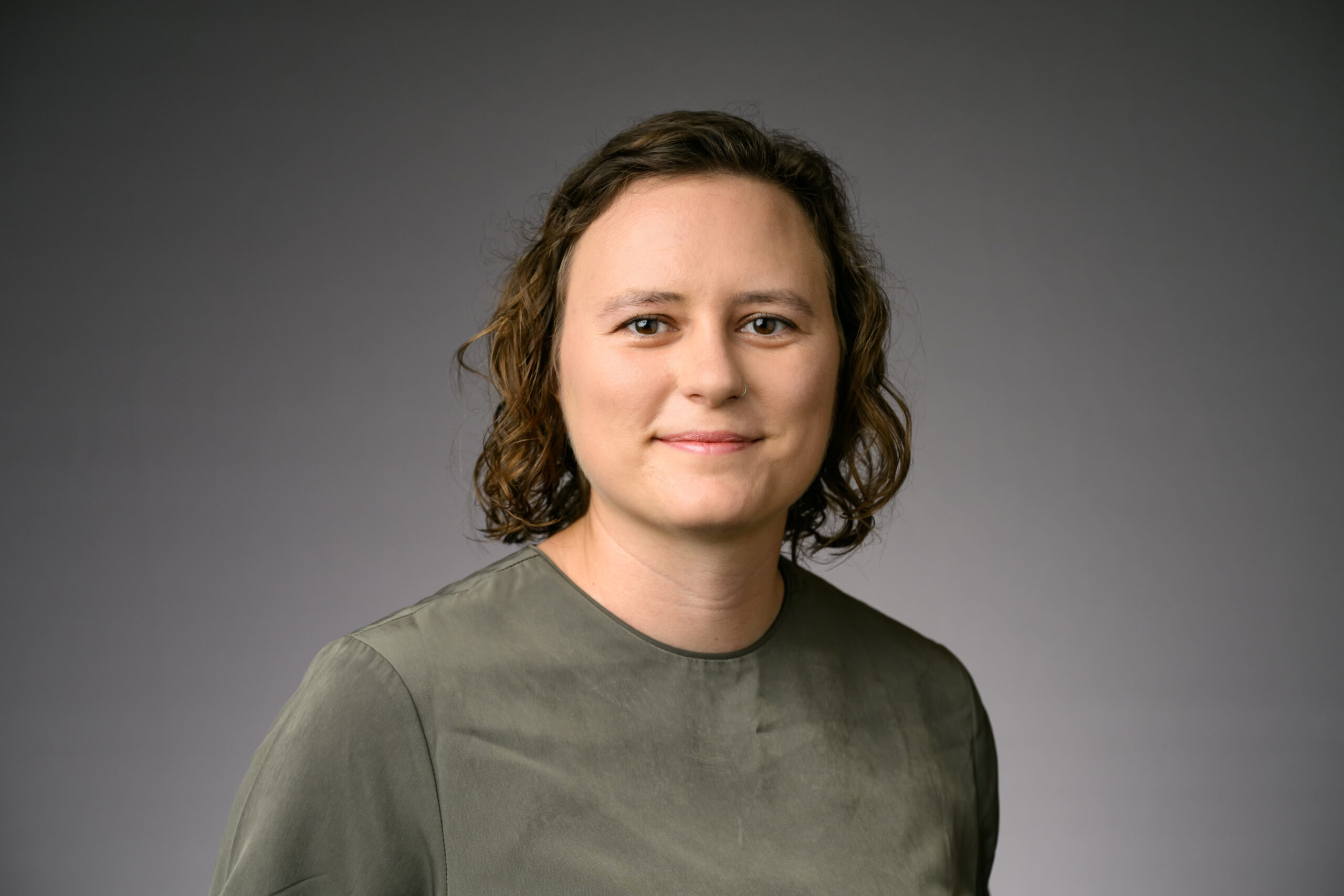 Leah Snavely wearing a green shirt in front of a grey background