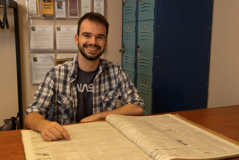 student posing with historical archives