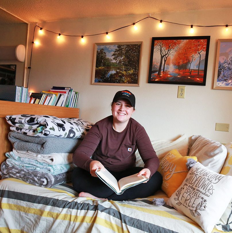 UWSP student sitting in their dorm room reading a book
