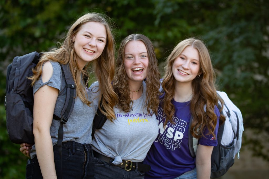Three female students posing in Pointer clothing outside of The Suites.