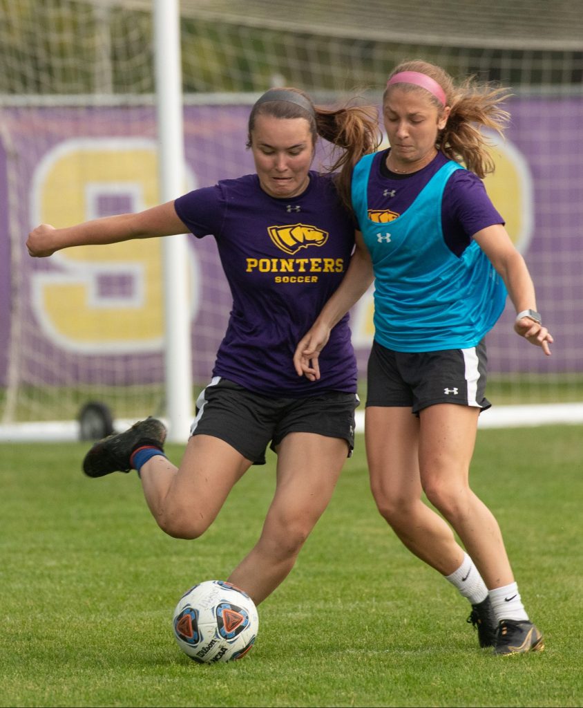Two female students playing soccer.
