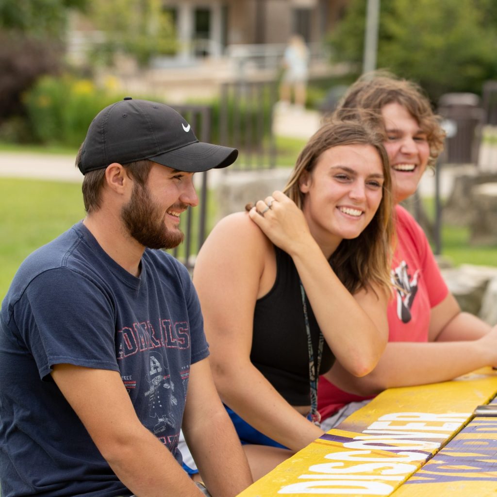 Group of students sitting at a picnic bench on campus