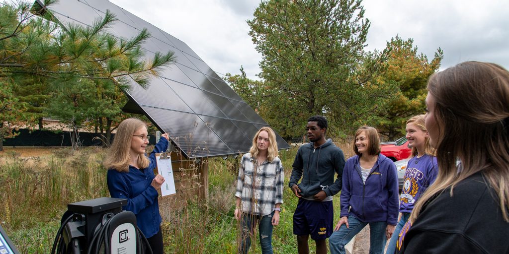 Professor and group of students looking at solar panel