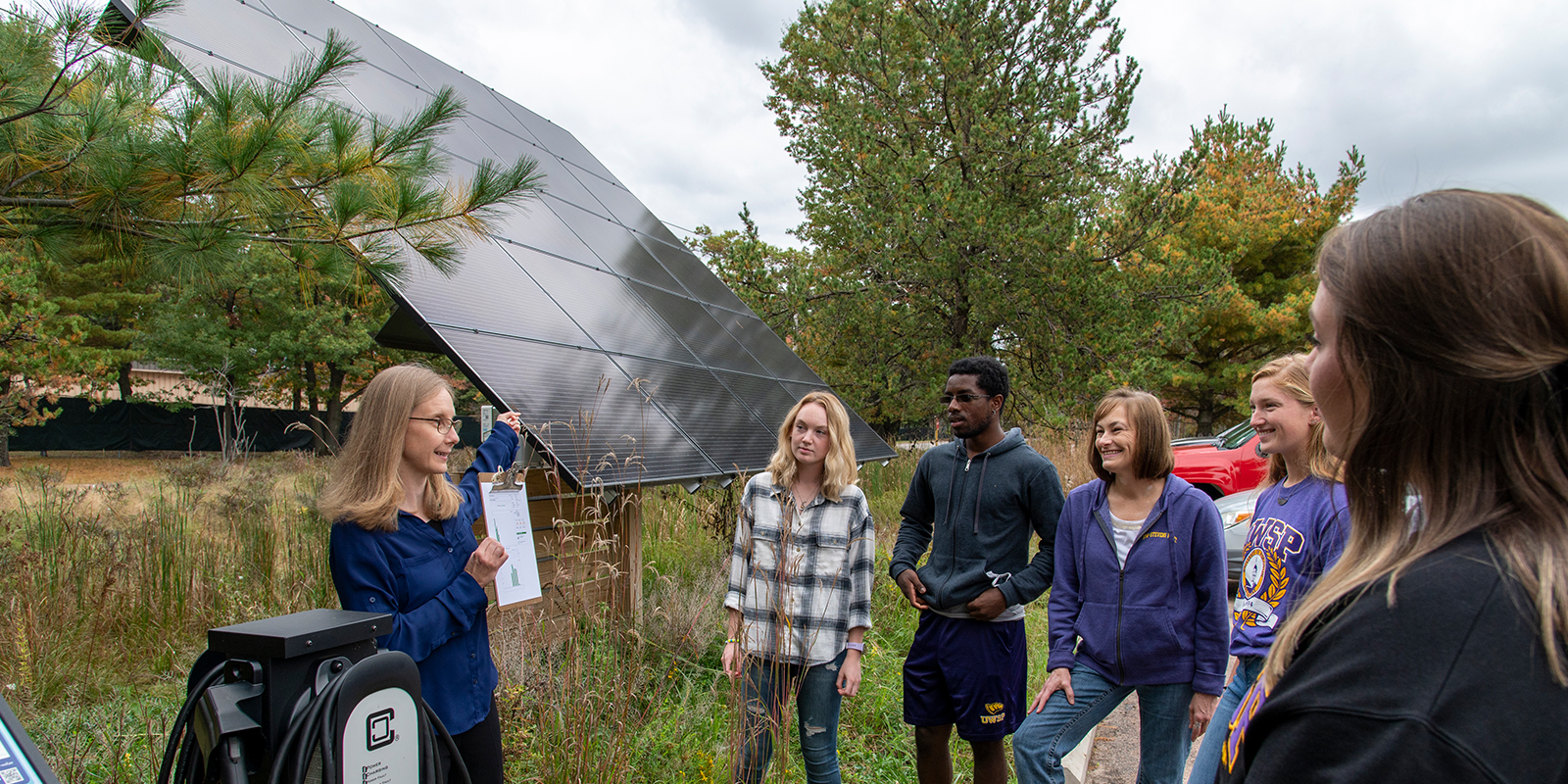 Professor and group of students looking at solar panel