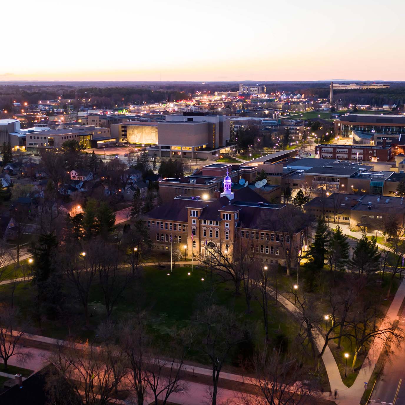 Stevens Point campus at night with the cupola lit purple.