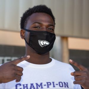 A male African American student posing outside our Dreyfus University Center in a black and white Pointer mask.