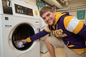 A smiling student pulling an item out of the laundry.
