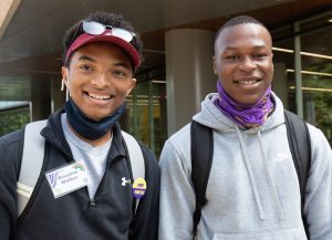 Two African American males posing and smiling in front of our Dreyfus University Center windows outside.