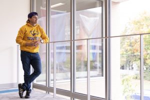 Student looking out the window of the Dreyfus University Center and wearing a gold UW-Stevens Point sweatshirt.