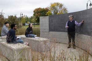 Political science students in a lecture with a professor at the Chemistry Biology Building outdoor classroom.