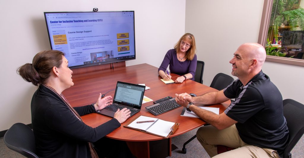 Three staff members sitting at a table.