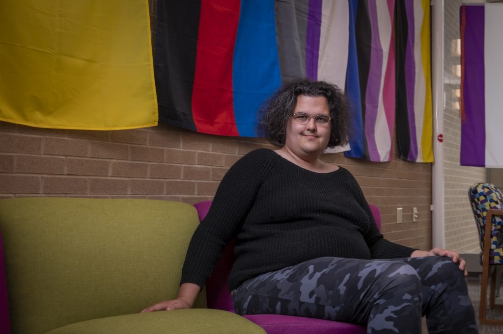 A student sitting on a couch in the Queer Resource Center.