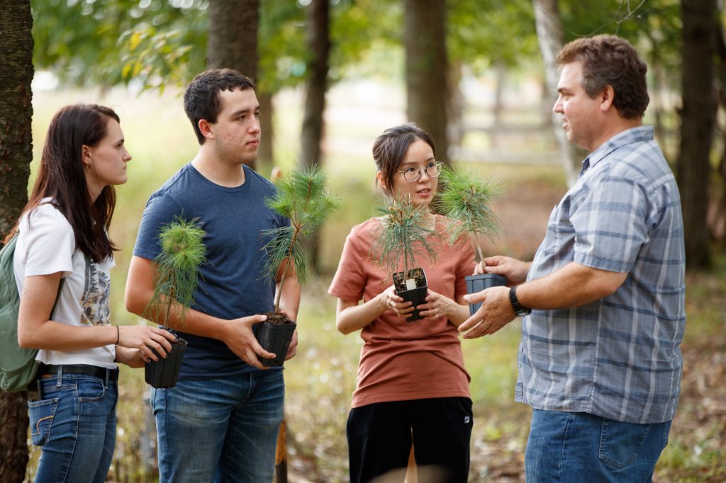 Three students working with forestry professor in Schmeeckle Reserve.