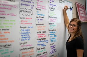 A student taking notes on a whiteboard during a health science class.