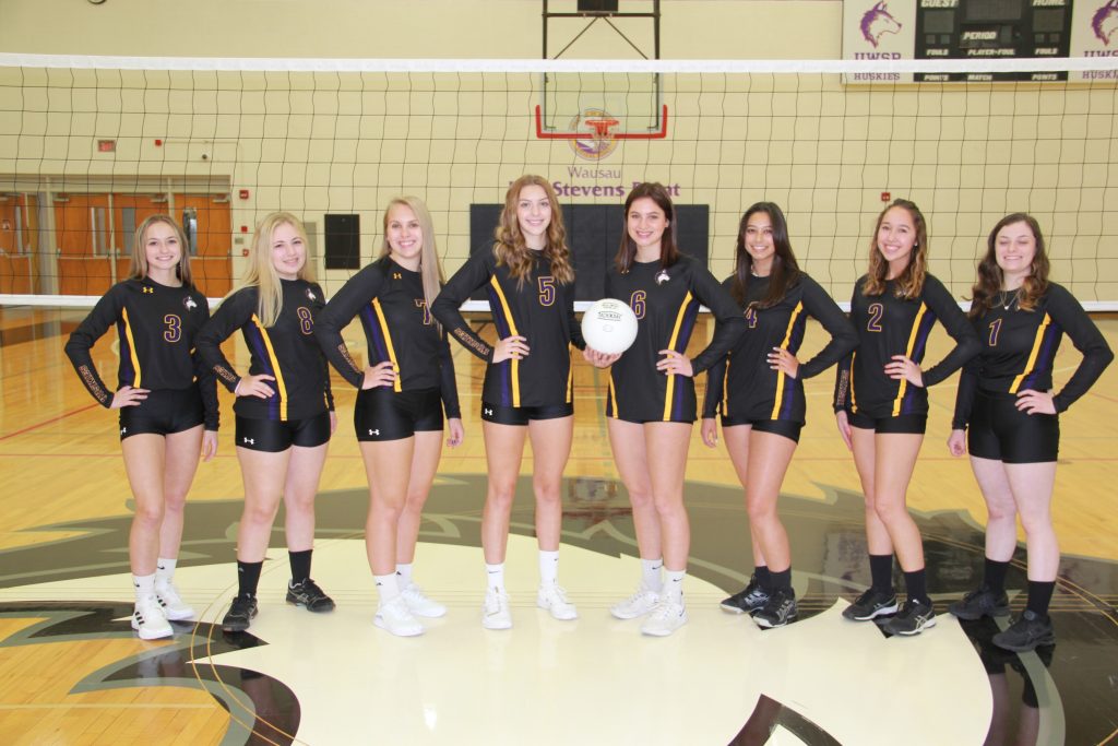 Wausau women's volleyball team players pose for a picture while holding a volleyball.
