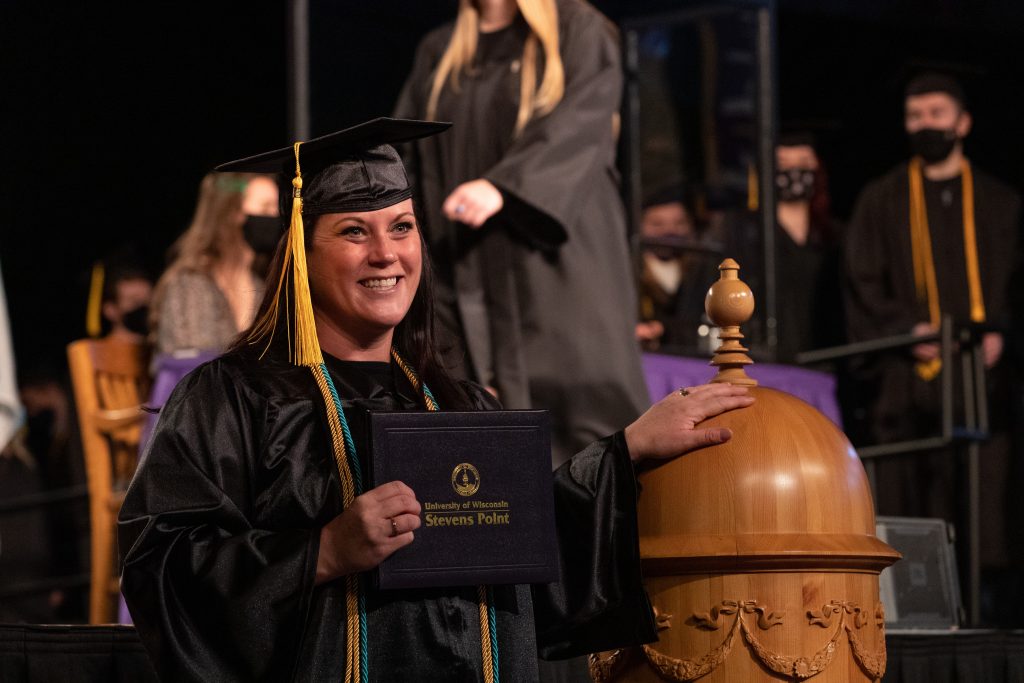 A graduate touching the cupola replica at Commencement.