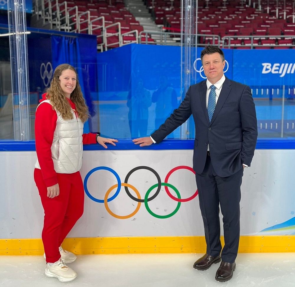 A male and female alumni posing on the ice at the Olympics.