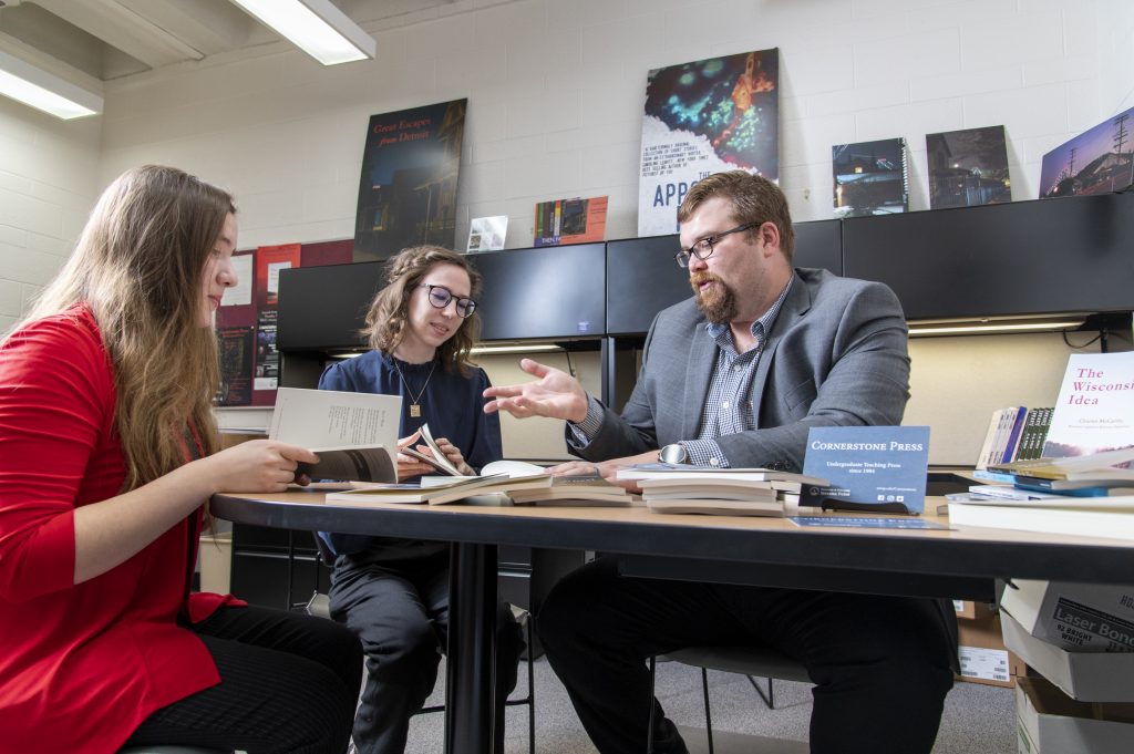 Two students working in the Cornerstone Press office with a faculty member.