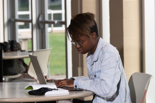 One female student is working on her computer in the study space above the Marshfield cafeteria.